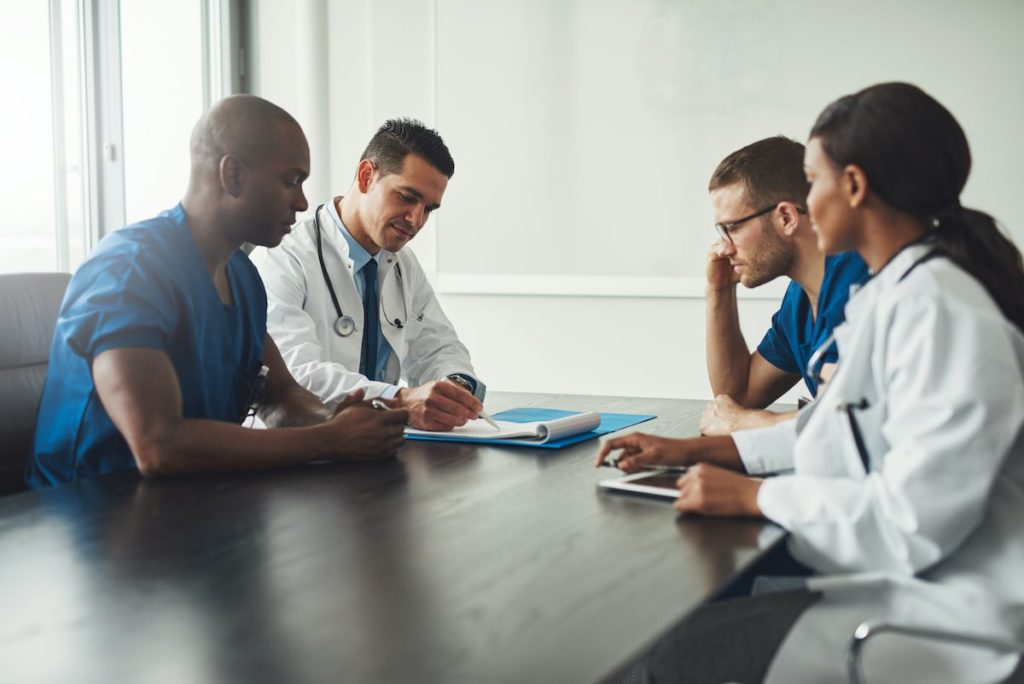 A group of medical professionals around a table having a meeting.