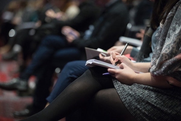 A woman attending a presentation, taking notes.